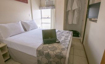 a bedroom with a bed , laptop on the table , and a robe hanging in the closet at Verona Hplus Long Stay