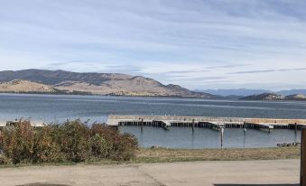 a dock extending into a large body of water , with mountains in the background and a road nearby at Big Arm Resort