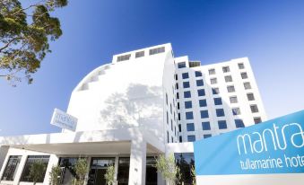 "a large white building with a blue sign that reads "" mare tulumärke "" and trees in front of it" at Mantra Melbourne Airport