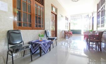 a modern living room with wooden doors , large windows , and furniture , including a dining table , chairs , and an outdoor balcony at RedDoorz Near Candi Ratu Boko