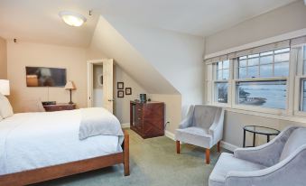 a spacious bedroom with a large bed , two chairs , and a tv . also a couch in the room at The Inn at Longshore