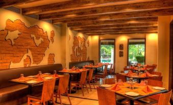 a restaurant with wooden tables and chairs , a map on the wall , and large windows at Country Roads