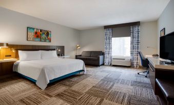 a hotel room with a king - sized bed , a couch , a chair , and a tv . also a dining table in the room at Hilton Garden Inn Nashville/Smyrna