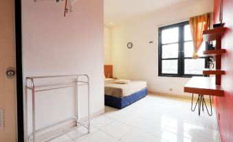 a clean and well - organized hotel room with a bed , window , and clothes rack on the floor at Griya Ayem