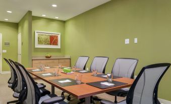 a conference room with a long table , six chairs , and various items on the table at Home2 Suites by Hilton Canton