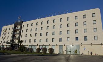 a modern hotel building with multiple floors and balconies , surrounded by trees and a clear blue sky at VIP Executive Santa Iria Hotel