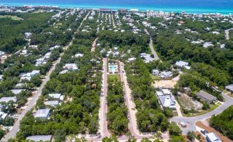 an aerial view of a residential area with a swimming pool surrounded by trees and buildings at Magnolia Cottages by the Sea by Panhandle Getaways