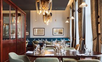 a dining room with a long wooden table surrounded by chairs , and a chandelier hanging above the table at Titanic Hotel Belfast