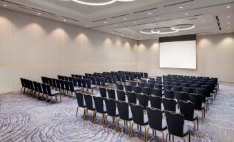 a large conference room with rows of chairs arranged in a semicircle , and a projector screen on the wall at Hyatt Regency Dulles