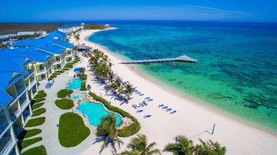 a beautiful beach resort with a large pool surrounded by palm trees and white sand at Wyndham Reef Resort Grand Cayman