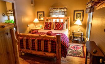 a cozy bedroom with a wooden bed , red and black checkered bedding , and two lamps on either side of the bed at RoosterComb Inn