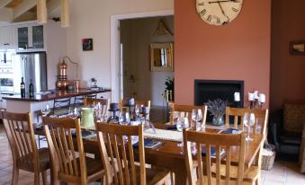 a wooden dining table with wine glasses and a clock on the wall in the background at The Summit Lodge