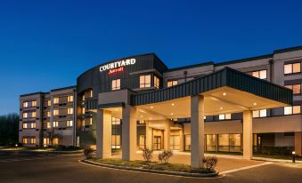 the exterior of a courtyard by marriott hotel at dusk , with its sign and columns lit up against a dark blue sky at Courtyard Burlington Mt. Holly/Westampton