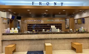 a modern , minimalist interior design of the front entrance with wooden accents and blue lettering , along with a bench and seating area at Toyoko Inn Oita Ekimae