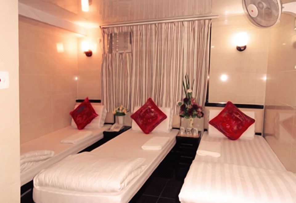 A room with two beds and red pillows, as well as a side table at Hong Kong Budget Hostel
