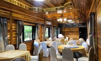 a large dining room with wooden walls , ceiling , and tables covered in white tablecloths and chairs at Hugpua Hotel