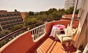 a balcony with a dining table and chairs , overlooking a cityscape and the ocean , under a clear blue sky at Alegria