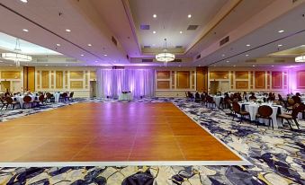 a large banquet hall with a dance floor and chairs , illuminated by purple lights and surrounded by tables at DoubleTree Boston North Shore Danvers