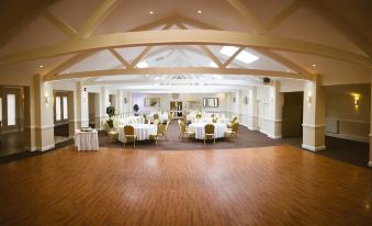 a large banquet hall with wooden floors and white walls , featuring several tables set for a formal event at Best Western Weymouth Hotel Rembrandt