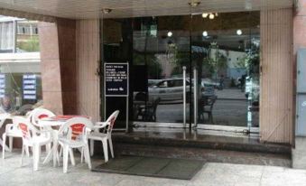 a glass door entrance to a building with white chairs and tables outside , creating an inviting atmosphere at Copacabana