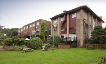 a large building with a balcony and several balconies is surrounded by green grass and trees at Premier Inn Burton On Trent East