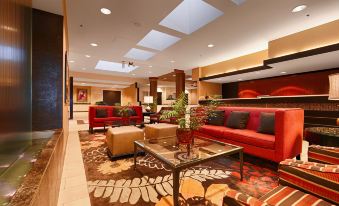 a modern hotel lobby with a red leather couch , brown leather chair , and wooden coffee table at Wyndham Minneapolis South/Burnsville