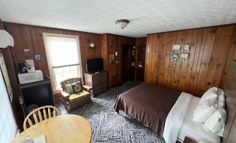 a cozy bedroom with wooden walls , a bed , and a tv , as well as a dining area with chairs and a table at Smoky Falls Lodge