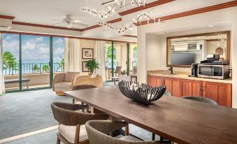 a spacious living room with a large wooden dining table , surrounded by chairs , and a view of the ocean at Grand Hyatt Kauai Resort and Spa