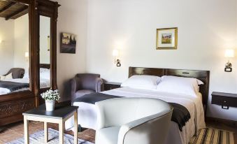 a cozy bedroom with a large bed , a chair , and a painting on the wall at Casale San Pietro