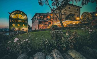 a picturesque town square with a sign for a hotel , surrounded by lush greenery and flowers at Hotel Ristorante la Pergola
