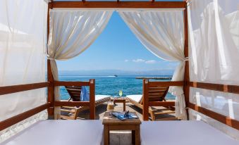 a beautiful beachfront view with two beds , chairs , and a table set up for relaxation at Grand Hotel Ontur Cesme