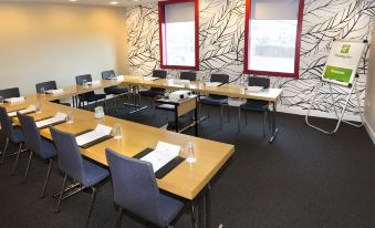 a conference room with several tables and chairs , a window , and a black and white patterned wall at Holiday Inn Salisbury - Stonehenge