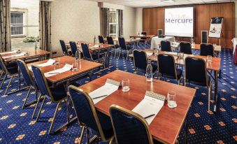 a conference room with blue carpeting , wooden tables , and chairs arranged in rows , ready for meetings or events at Mercure York Fairfield Manor Hotel