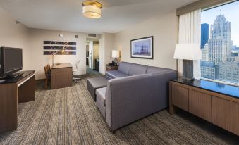 a modern living room with a gray couch , wooden coffee table , and framed art on the wall at Embassy Suites by Hilton Chicago Downtown Magnificent Mile
