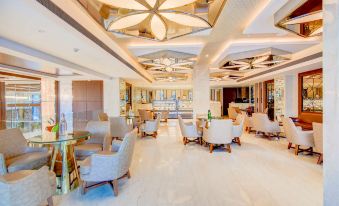 a spacious , well - lit room with white marble floors and gold accents , containing several chairs arranged around a coffee table at Radisson Blu Gorakhpur