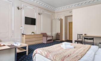 a large bed with a white comforter is in the middle of a room with blue carpeting at Alexander Hotel