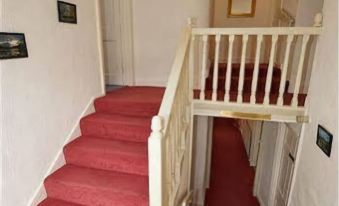 a white staircase with red carpet leading up to the second floor of a house at The White House Guest House