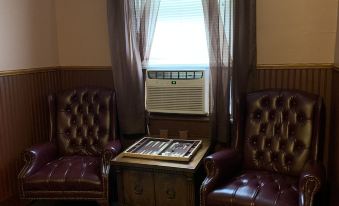 a room with two brown leather chairs facing each other and a window behind them at The Hotel Belvidere