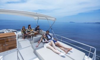 a group of people , including a man and a woman , are enjoying a boat ride on a lake , with some of them lounging on sun at Malibu Hotel