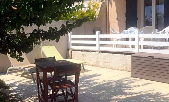 a backyard with a patio set , chairs , and a dining table , surrounded by trees and grass at Les Amandiers