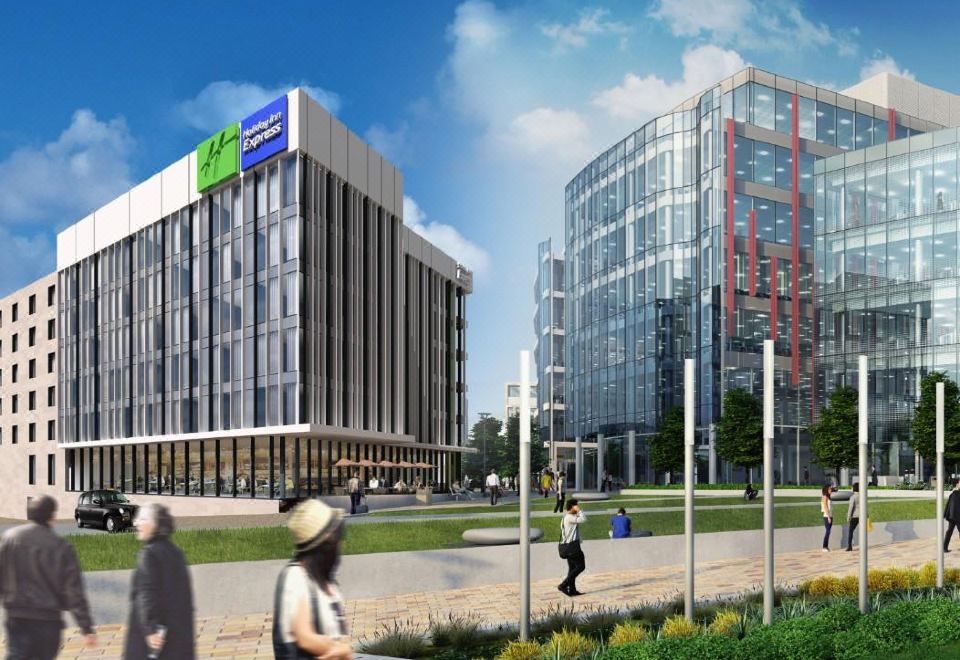 a group of people walking on a sidewalk in front of a tall building , possibly a hotel or office building at Holiday Inn Express Stockport