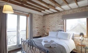 a cozy bedroom with a large bed , wooden beams on the ceiling , and a brick wall at Rocksalt