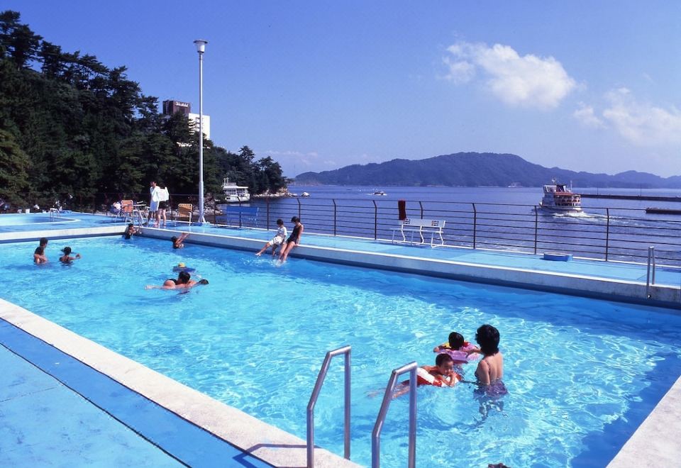 a group of people are enjoying a day at the pool with boats in the background at Todaya