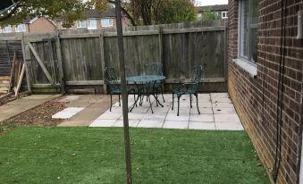 a small backyard with a dining table and chairs set up for a meal , surrounded by a grassy area at Sunny City