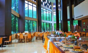 a large , modern restaurant with multiple dining tables and chairs , as well as a buffet - style food stand at Hotel Grand Baron