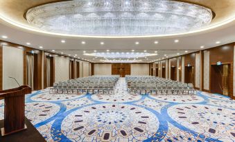 a large conference room with rows of chairs arranged in a semicircle , and a large rug covering the floor at Sheraton Grand Samsun Hotel