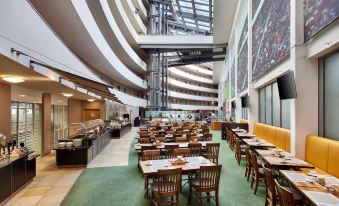 a large , modern dining room with multiple tables and chairs , as well as a buffet table filled with food at Lindner Hotel Leverkusen Bayarena