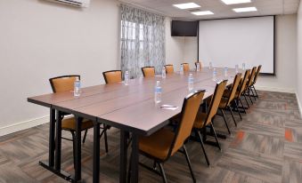 a long wooden table with chairs and water bottles is set up in a conference room at Residence Inn Boston Andover