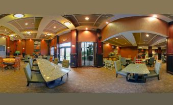 a panoramic view of a restaurant with several tables and chairs , a bar , and a doorway at Homewood Suites by Hilton Bloomington