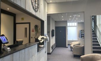 a modern office space with white walls , gray carpeting , and large windows , featuring a reception desk and seating area at Escape Hotel